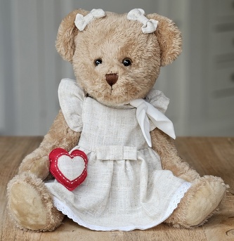Plyšový medvěd v béžových šatech s šátkem